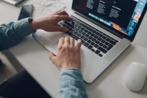 person wearing long-sleeve top working on laptop